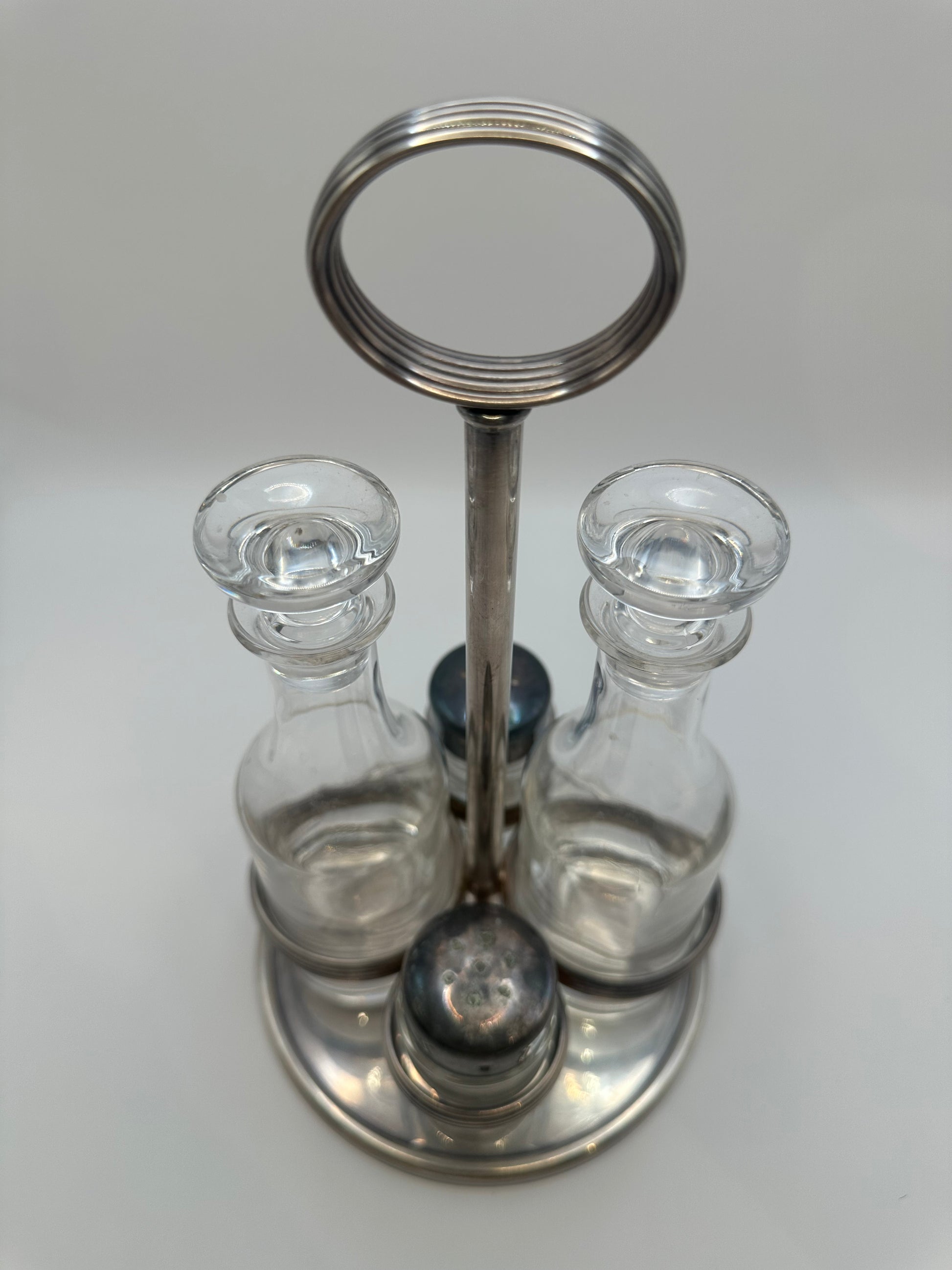 MCM silverplate cruet set from above showing dark shaker caps and glass stoppers.