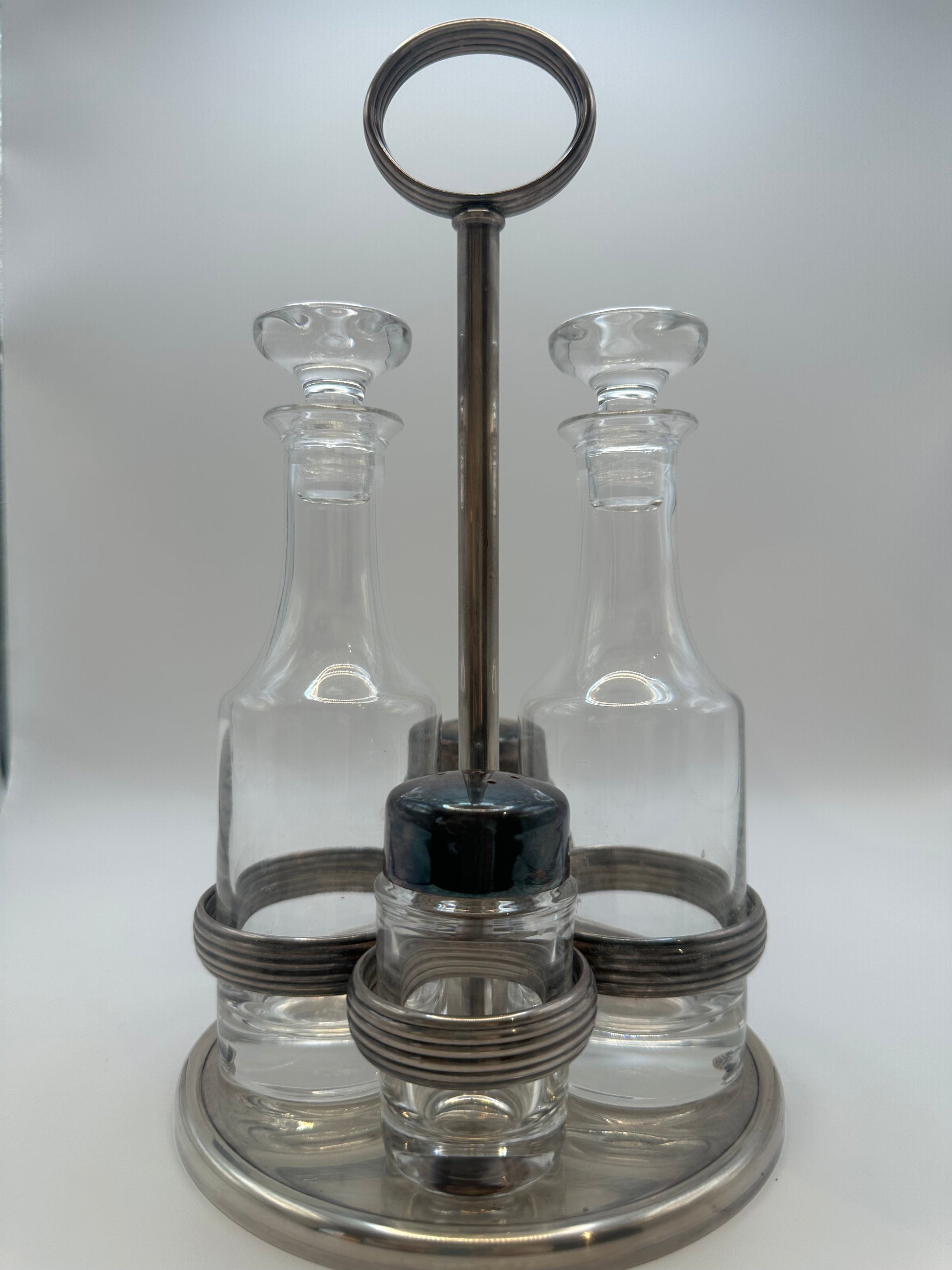 MCM silverplate cruet set, two stoppered glass bottles flanking the ring-handled stand.