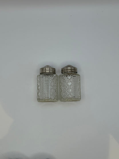 Two cut-glass shakers with silver tops from the cruet set, side by side.
