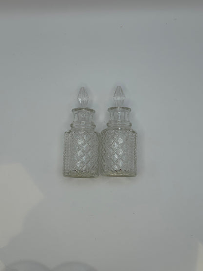 Two diamond-cut glass cruets with pointed glass stoppers from the set.