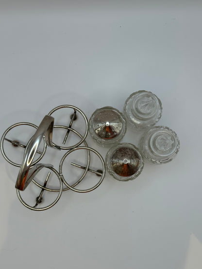 Disassembled cruet set: silverplate stand, two shaker tops and two stoppered cut-glass bottles.