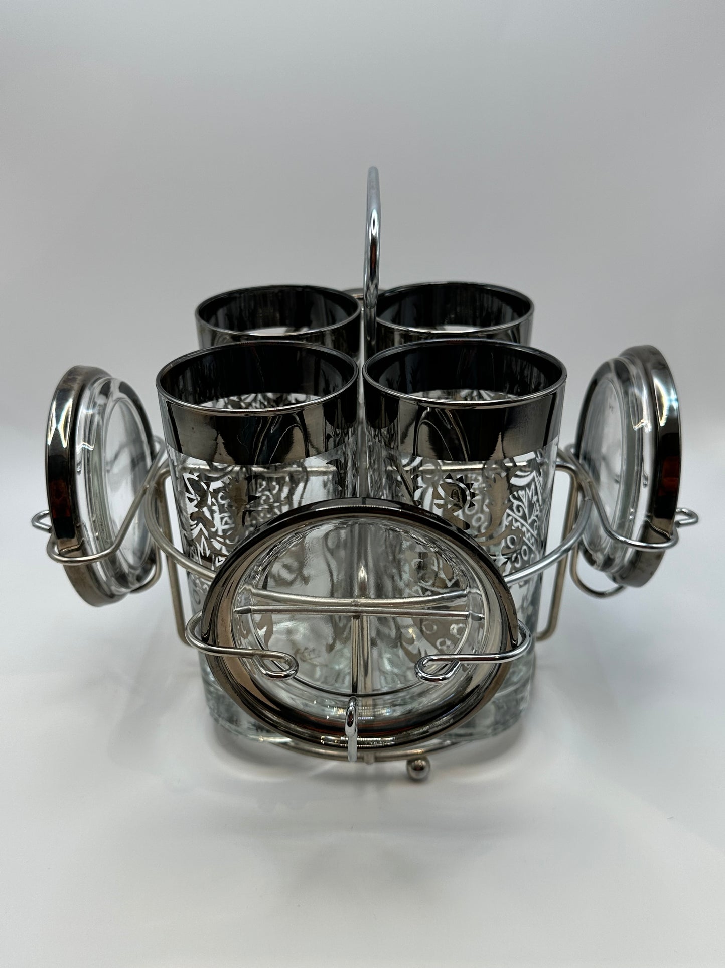 MCM Kimiko barware set of four glasses and coasters in chrome caddy, angled view.