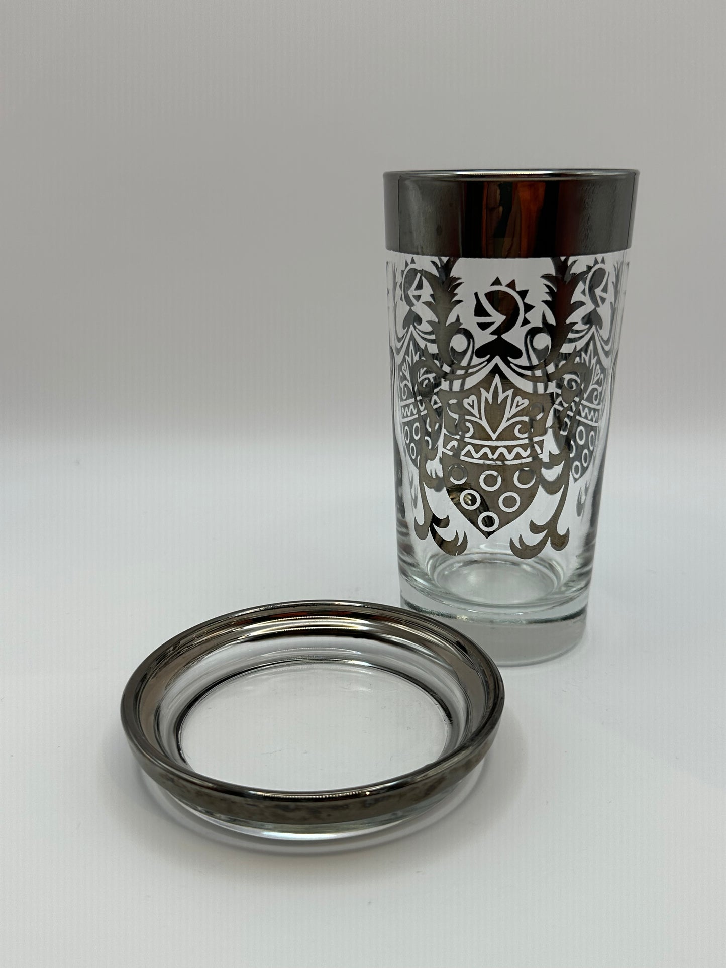 Kimiko highball glass with silver mercury-fade rim and baroque pattern, beside a matching coaster.