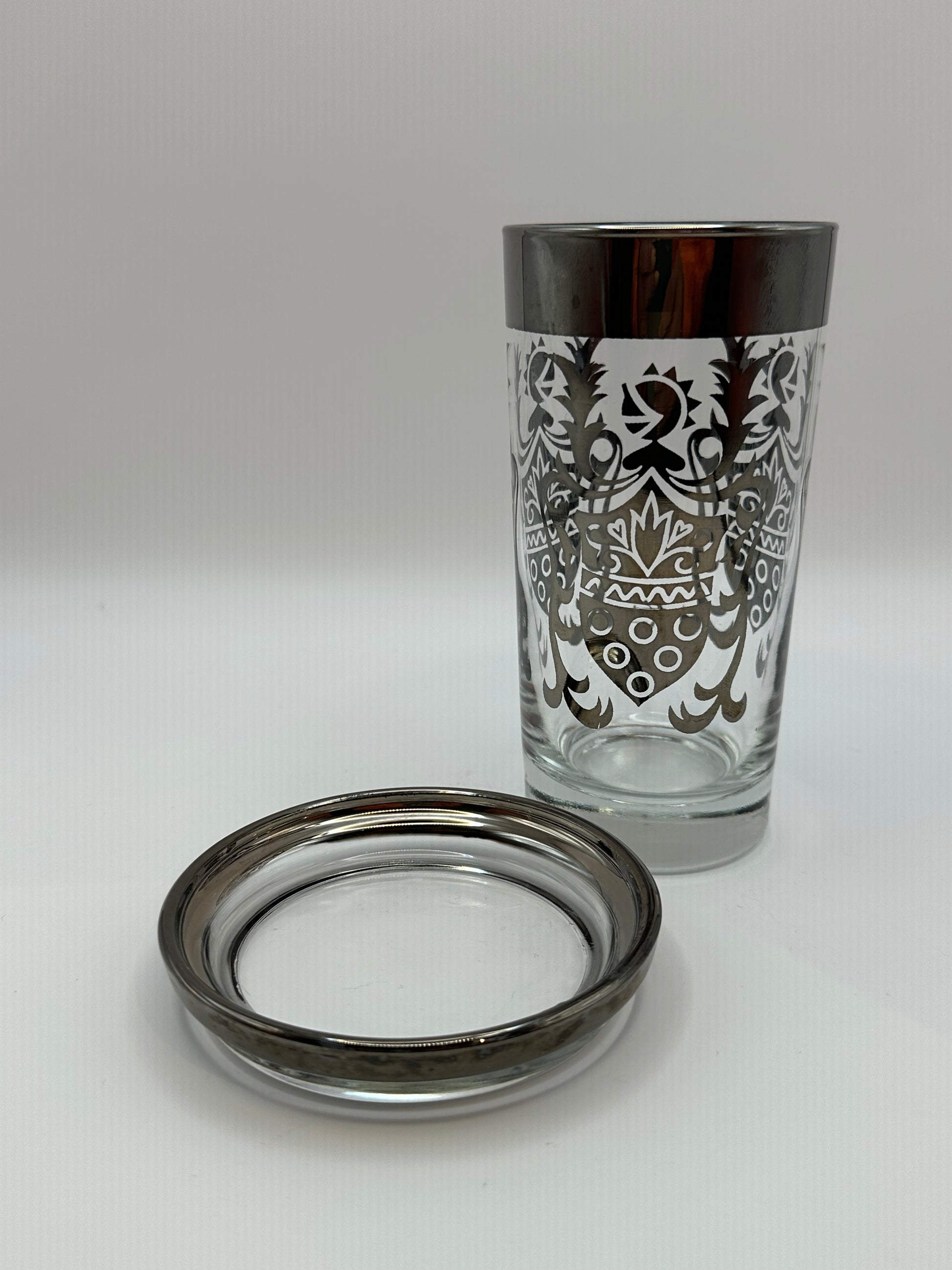 Kimiko highball glass with silver mercury-fade rim and baroque pattern, beside a matching coaster.
