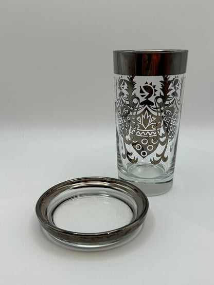 Kimiko highball glass with silver mercury-fade rim and baroque pattern, beside a matching coaster.