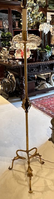 Gilt floor lamp full view with shade, standing on showroom floor near antiques