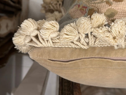 Close-up of pillow's cream cotton tassel fringe and beige velvet piped edge