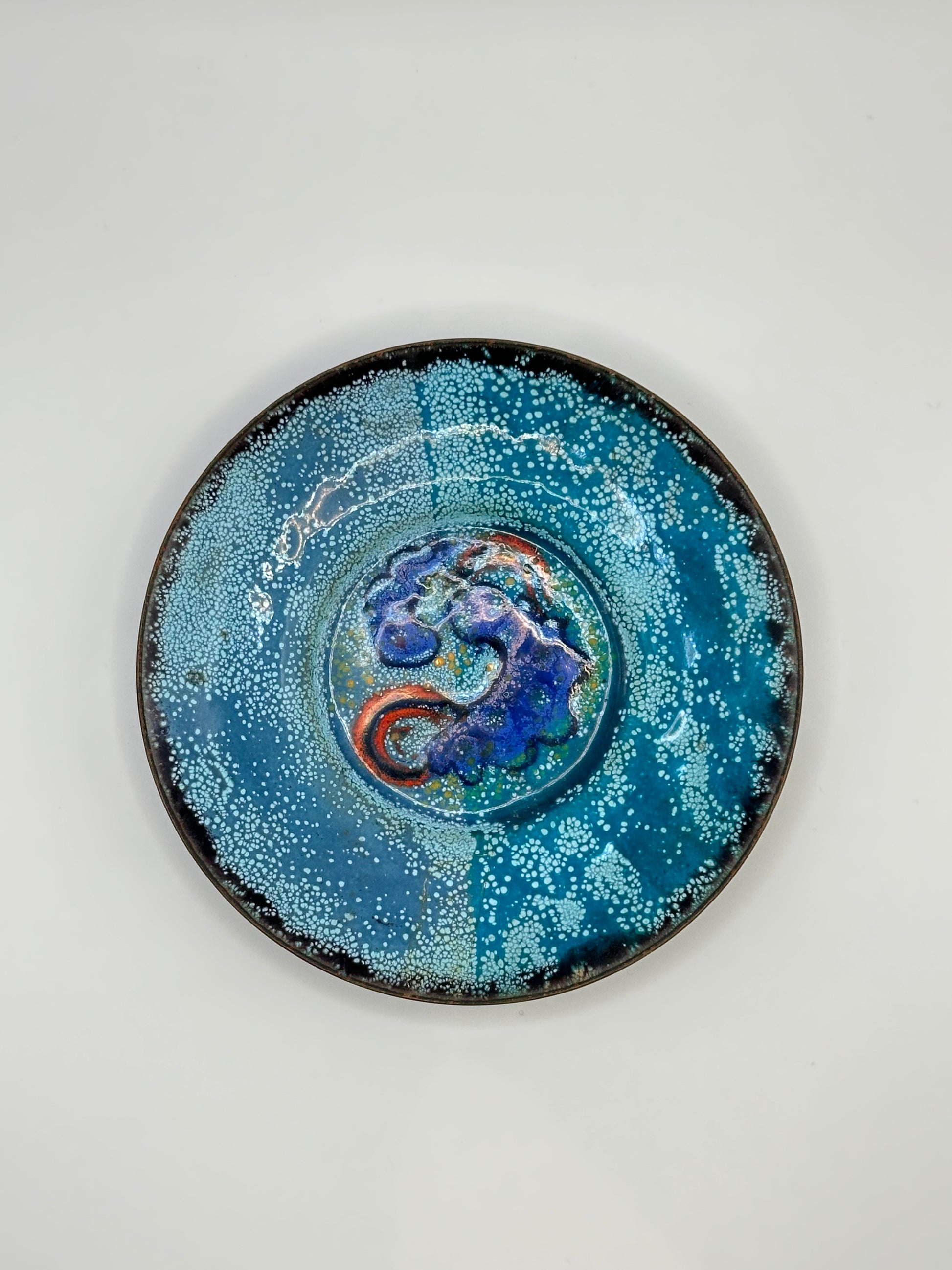 Doris Hall enamel-on-copper dish, blue speckled glaze with cobalt and red swirl center, top view