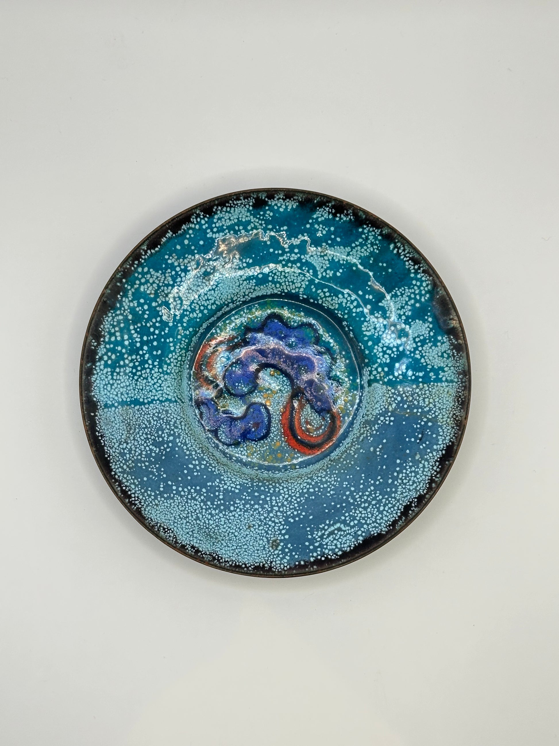 Doris Hall enamel dish, teal speckled glaze with blue and red abstract swirl, front view