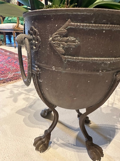 Side view of empty bronze jardiniere on tripod claw legs with ring handle