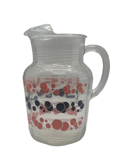 Matching glass pitcher with bands of red and black atomic polka dots and a ribbed body