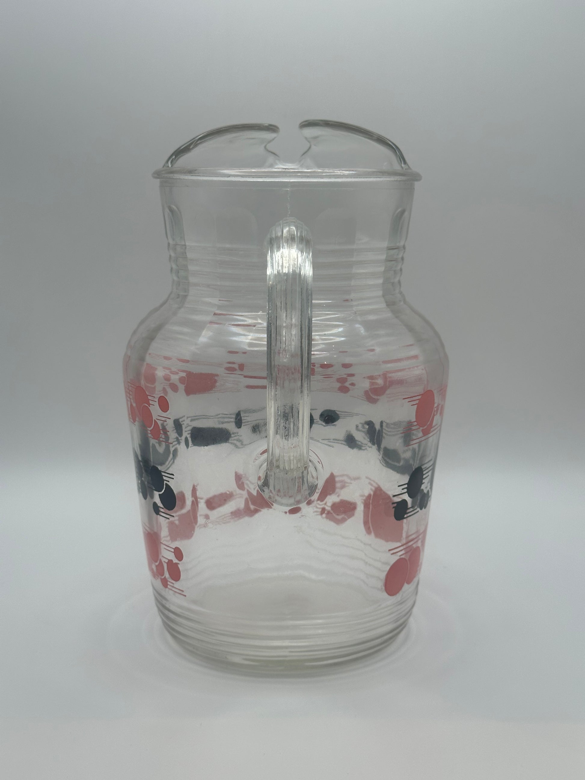 Back of the glass pitcher showing the clear ribbed handle and faint polka-dot pattern