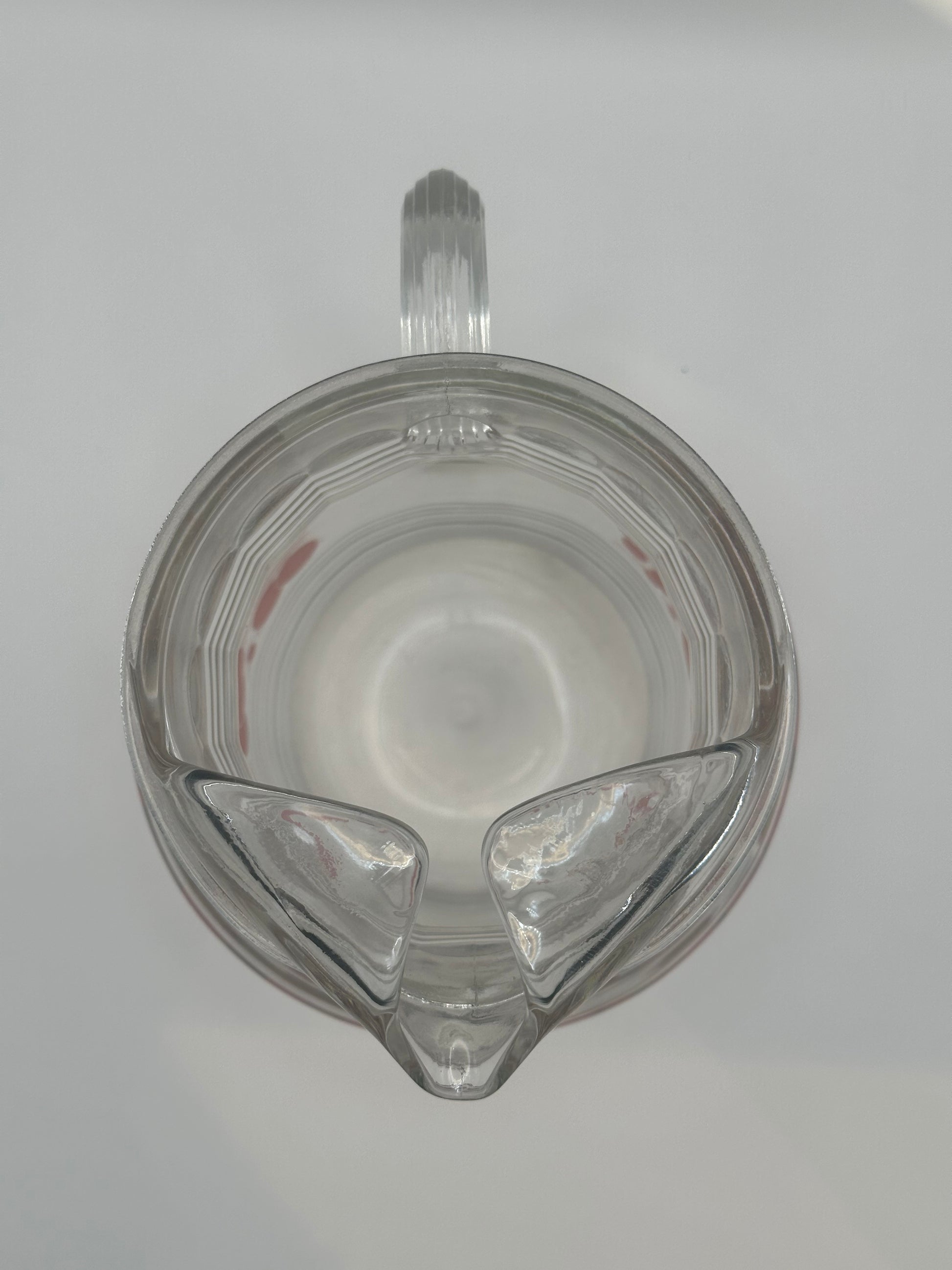 Top-down view into the glass pitcher showing its spout, handle and ribbed clear base