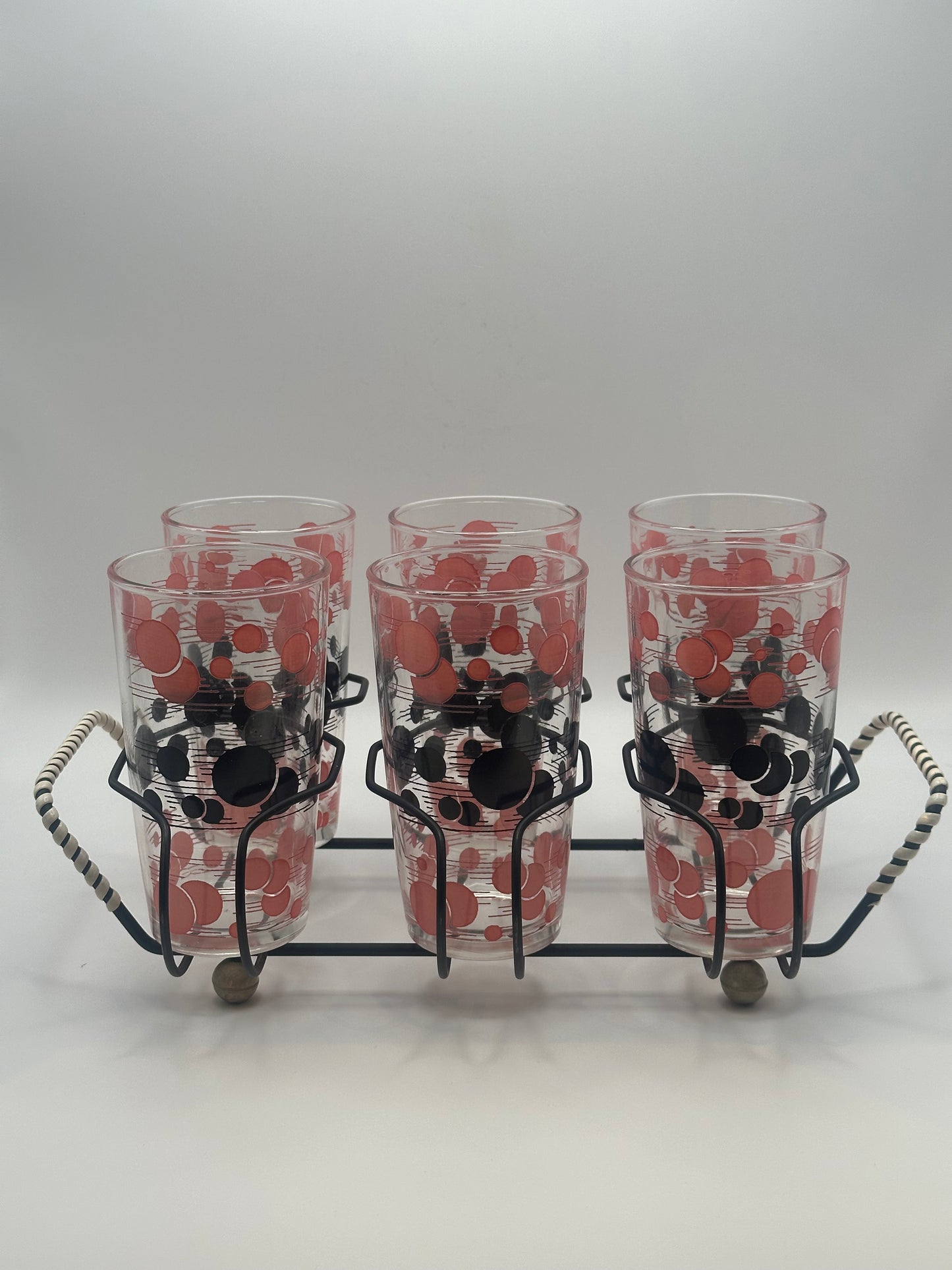 Front view of all six atomic polka-dot tumblers arranged in the black wire caddy