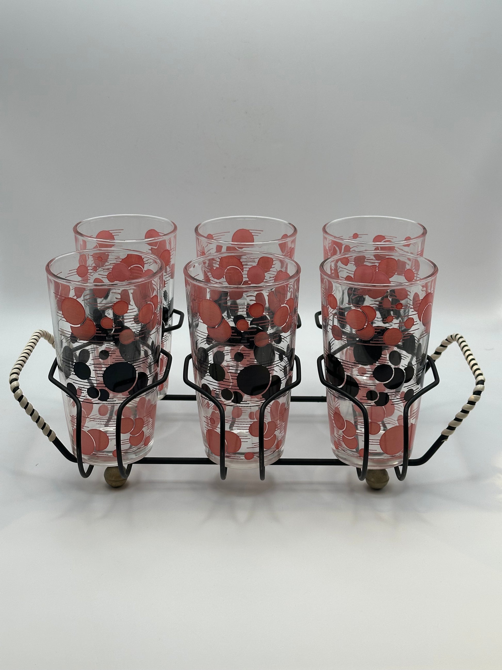 Six red and black polka-dot tumblers grouped together in the black wire carry caddy