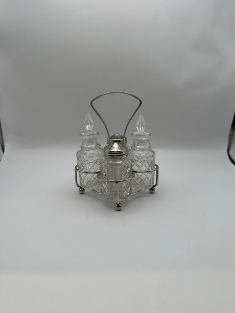 Cut-glass cruet set in silverplate wire stand with arched handle, front view.