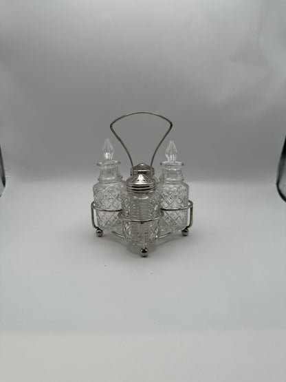 Cut-glass cruet set in silverplate wire stand with arched handle, front view.