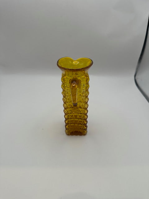 Front view of amber pressed-glass cruet showing pinched spout and applied handle