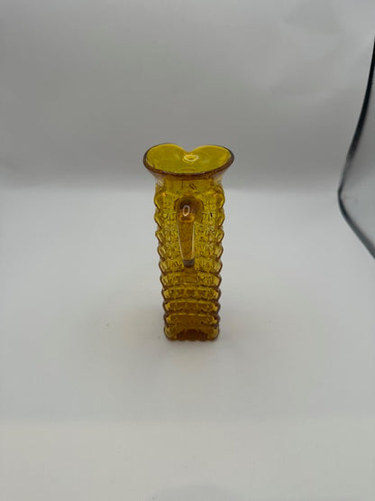 Front view of amber pressed-glass cruet showing pinched spout and applied handle