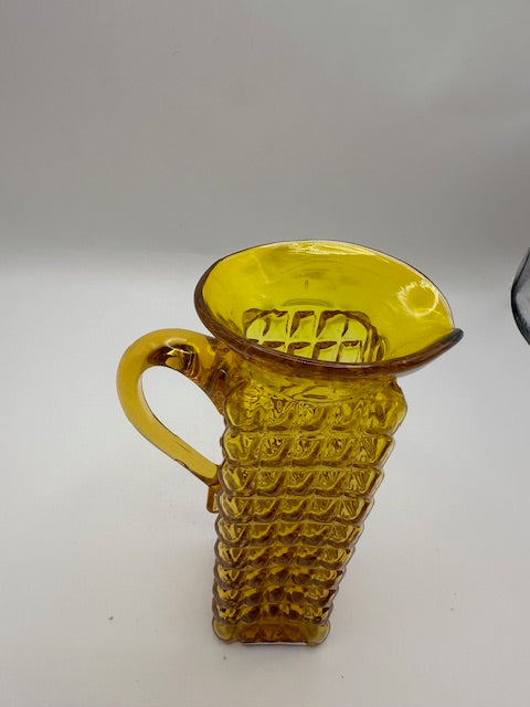 Angled view of amber pressed-glass cruet showing flared spout and textured body