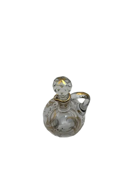Clear glass cruet with gold botanical decoration and faceted ball stopper set in place, top-down angled view