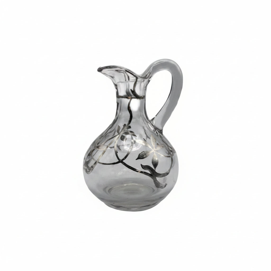 Vintage clear blown glass cruet bottle with silver floral overlay, pinched spout and handle, front view