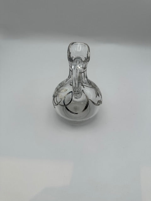 Top-down view of clear glass cruet showing spout, handle and silver overlay detailing