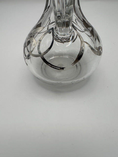 Close-up of clear glass cruet base showing bulbous body and silver floral overlay
