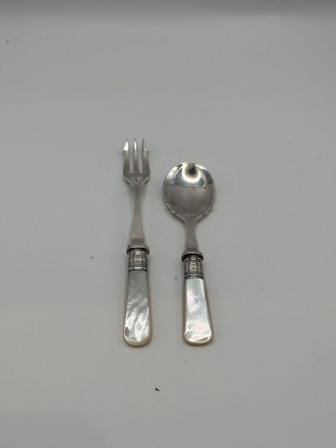 Silver plate and mother-of-pearl fork and spoon set laid on a pale grey surface