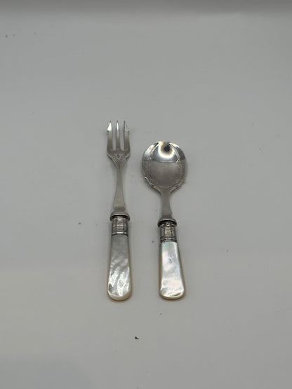 Silver plate and mother-of-pearl fork and spoon set laid on a pale grey surface