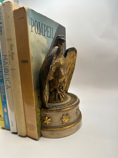 One Borghese gilt eagle bookend in use, holding upright books including a volume titled Pompeii