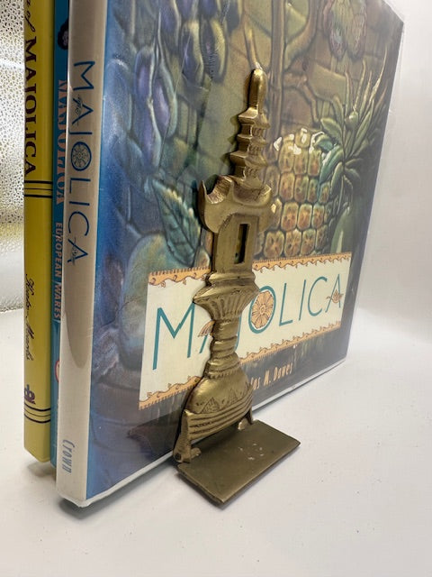 Vintage brass pagoda bookend in use holding upright Maiolica reference books