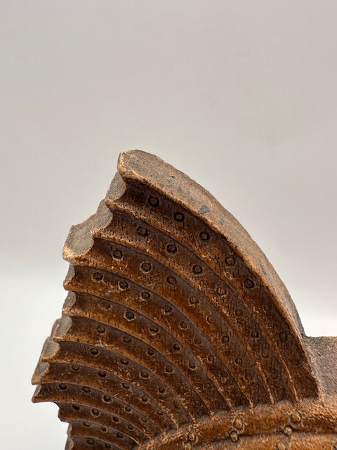 Detail of carved wood sailfish bookend's serrated fin edge and weathered finish