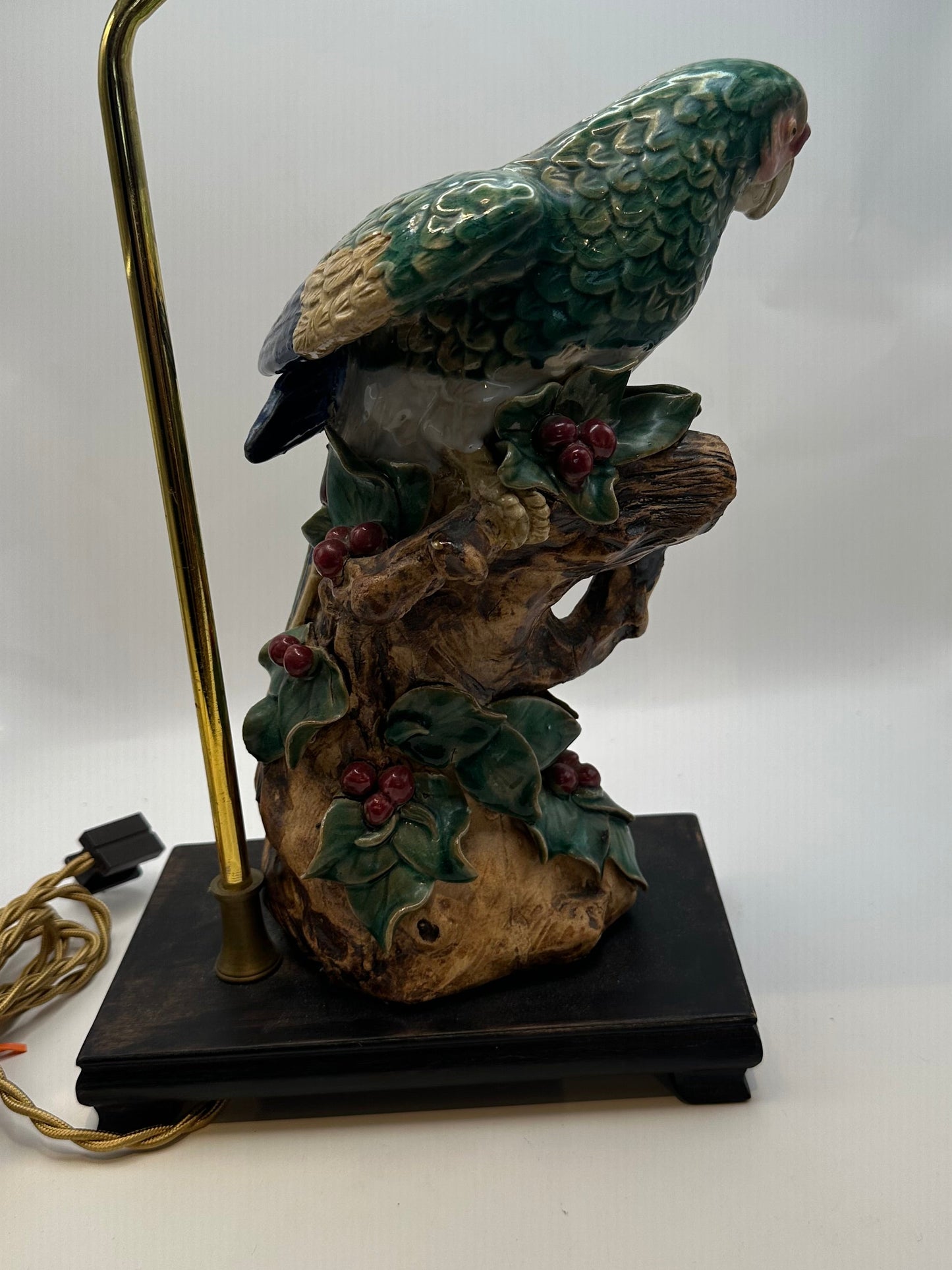 Rear view of the parrot lamp showing blue and green tail feathers, berried branch and wood base