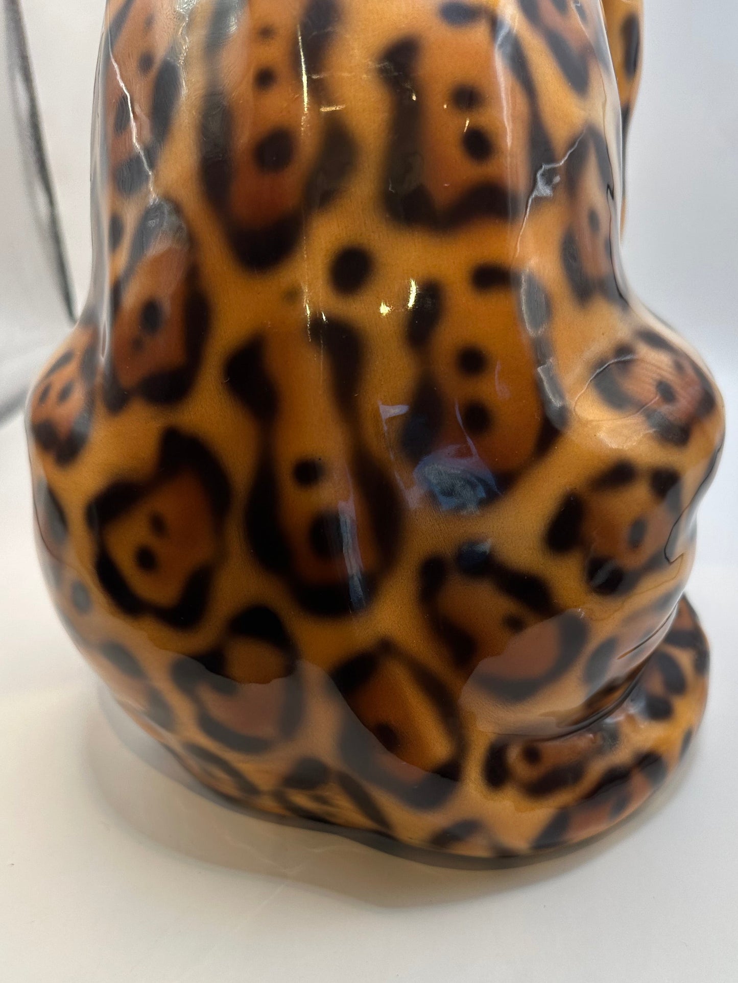 Close-up of the leopard figure's glossy hand-painted black-and-amber spotted glaze