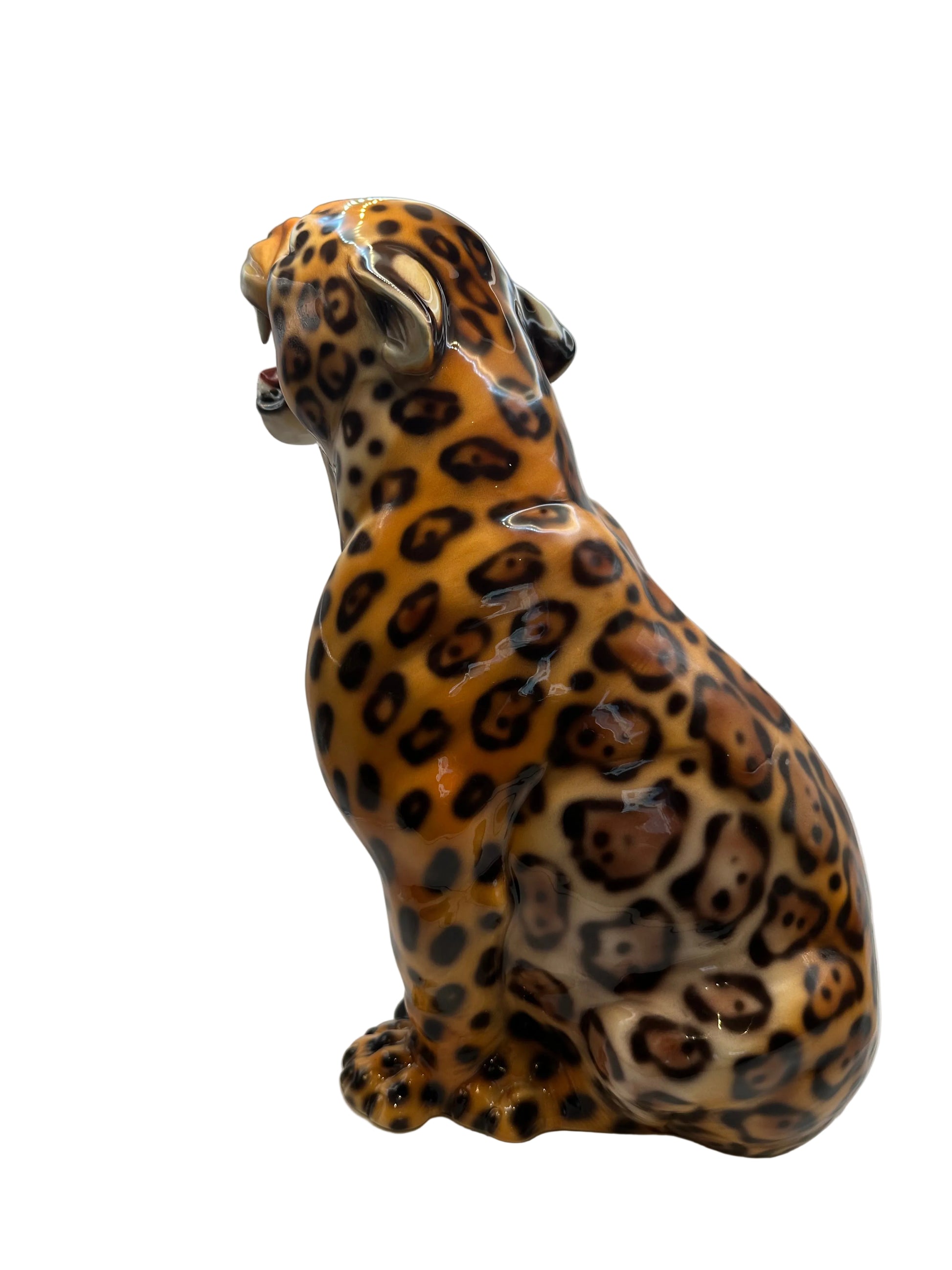 Side profile of the seated ceramic leopard showing the glossy spotted body