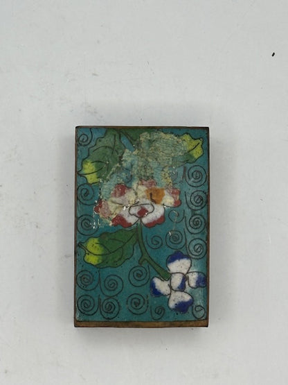 Close-up of the cloisonne cover's enamel flowers showing surface wear and loss on one side