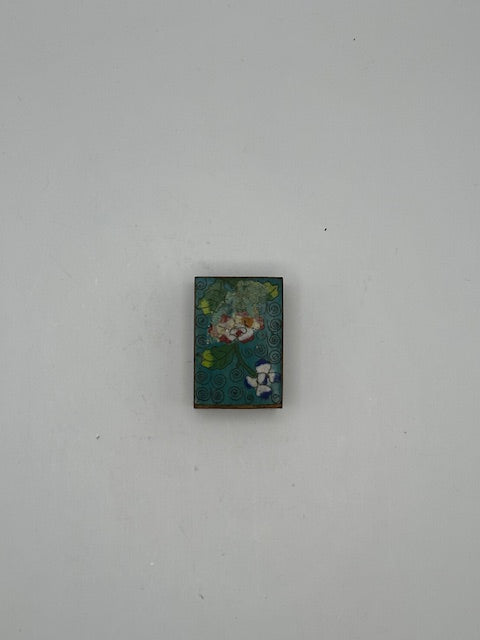 Angled view of the aqua cloisonne matchbox cover with floral enamel and spiral ground