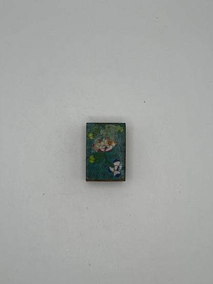 Angled view of the aqua cloisonne matchbox cover with floral enamel and spiral ground