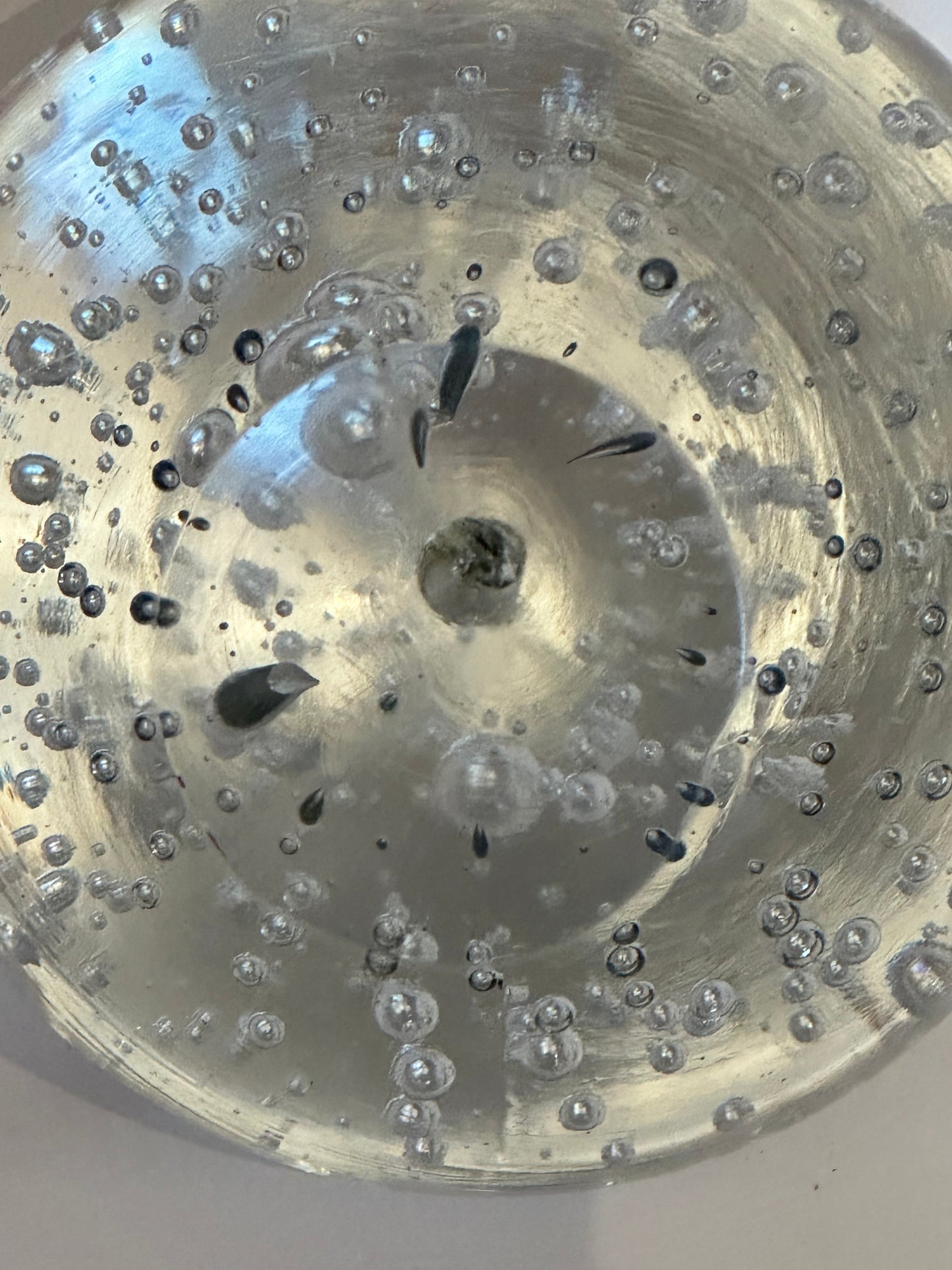 Extreme close-up inside vintage bubble glass sphere showing bubbles and dark inclusions