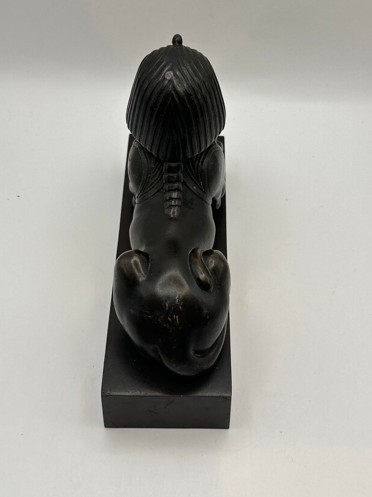 Rear view of vintage bronze sphinx statue showing headdress back and haunches on base