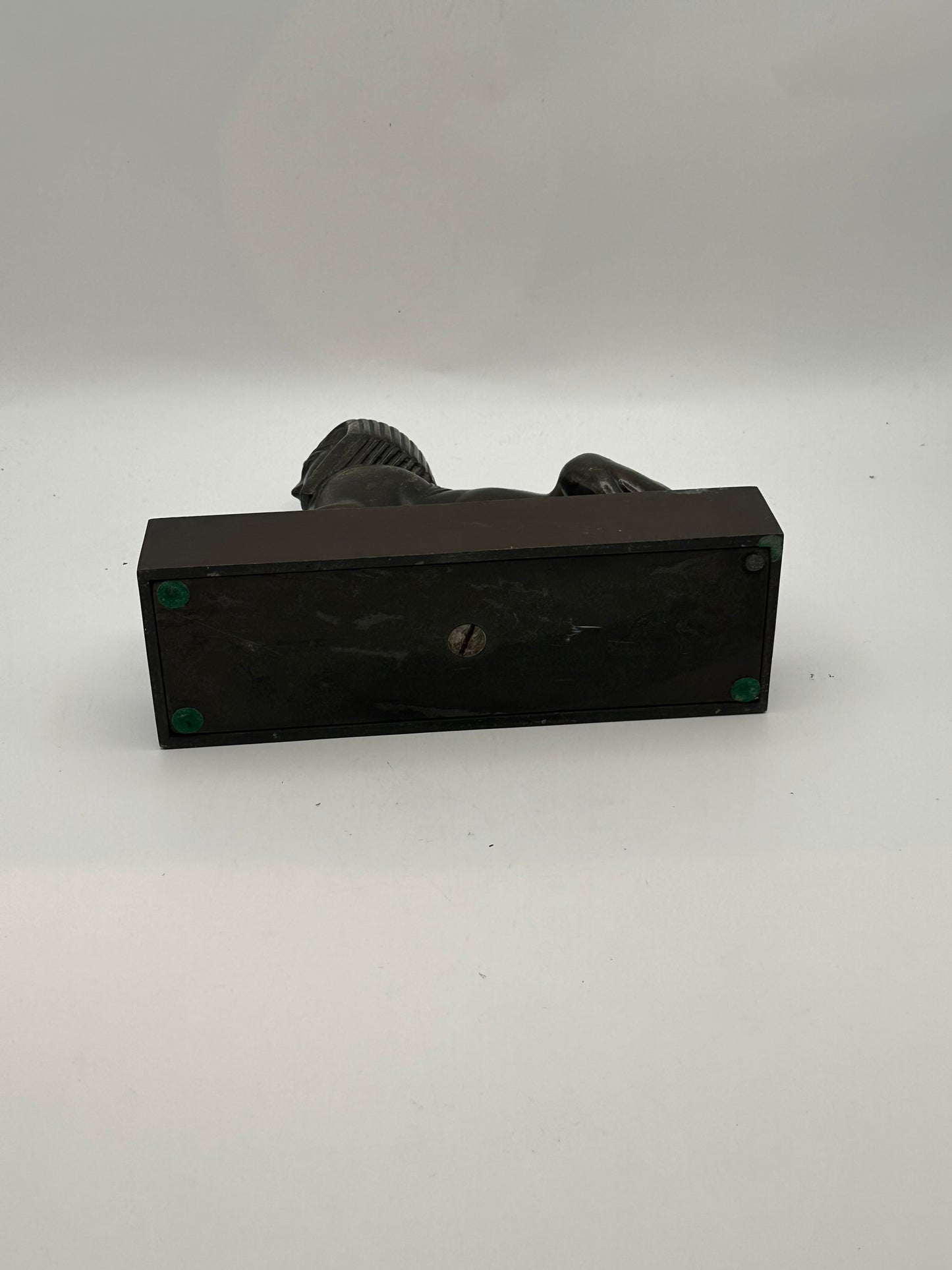 Underside of vintage bronze sphinx statue showing black base with felt pads and screw