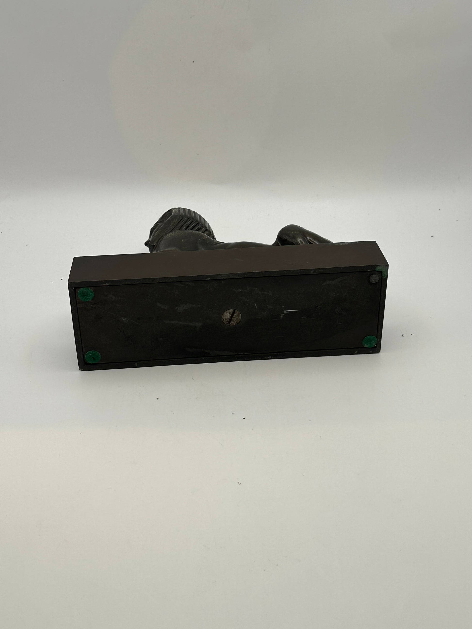 Underside of vintage bronze sphinx statue showing black base with felt pads and screw