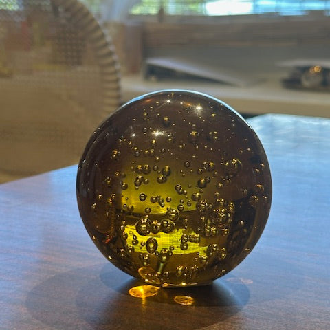 MCM amber bubble glass sphere lit from within, resting on a wood surface