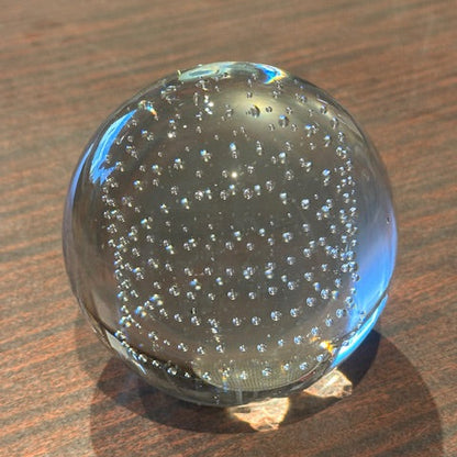 MCM controlled-bubble glass sphere resting on a wood table, clear orb with internal bubbles