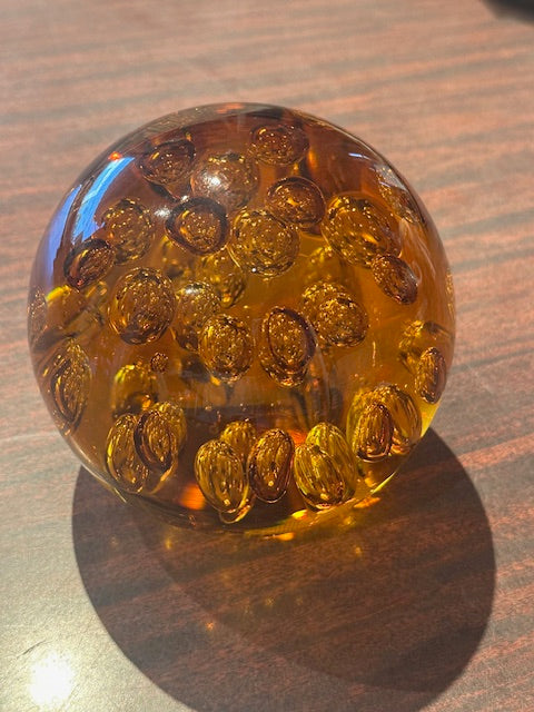 MCM amber bubble glass sphere lit warmly, resting on a wood table