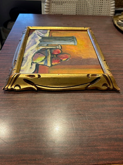 Vintage framed still life painting lying on wood table, angled view showing ornate gilt corner
