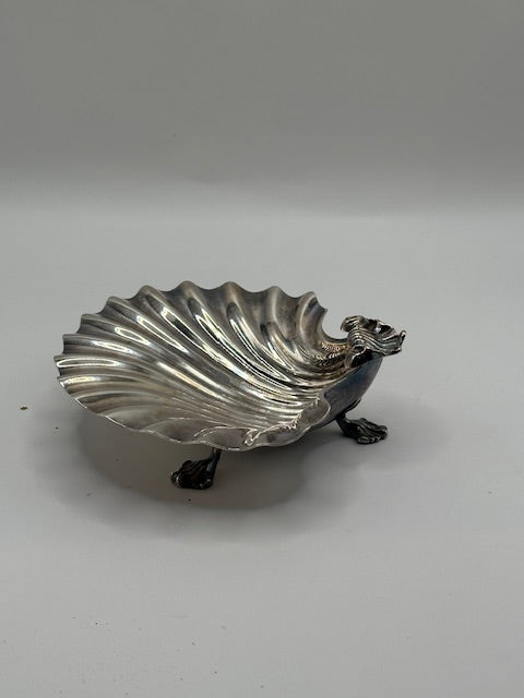 Vintage silver plate shell dish raised on claw feet, angled view with figural creature handle