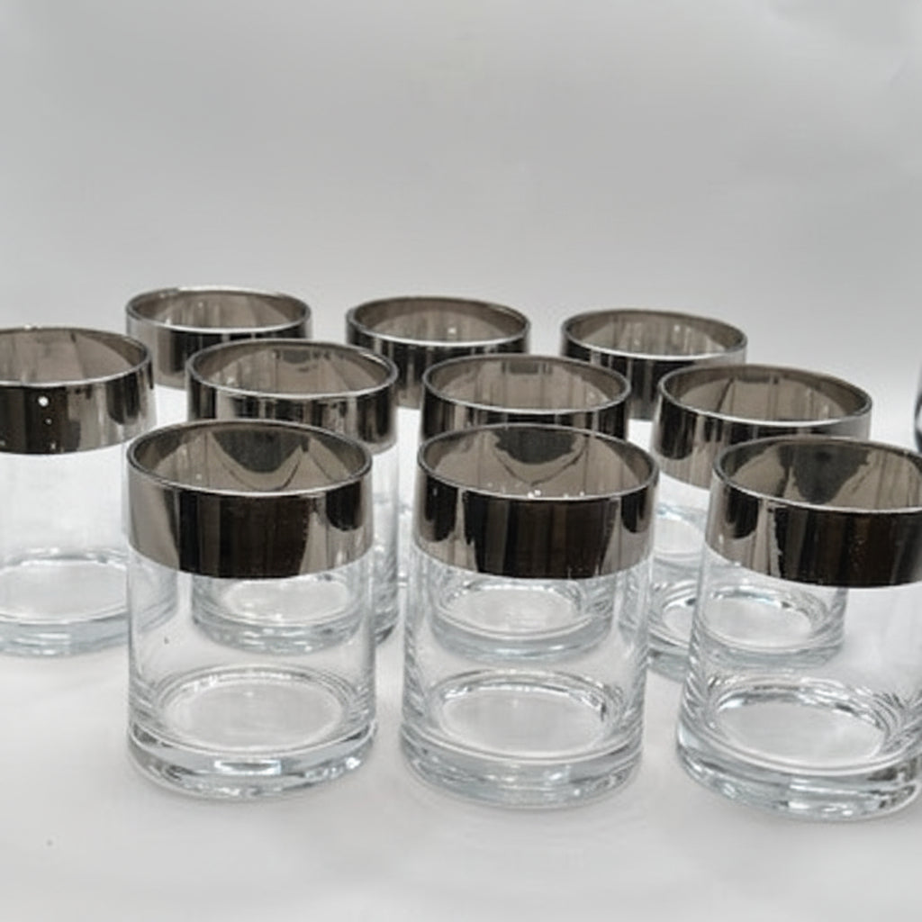 MCM silver-rimmed rocks glasses clustered, showing the wide mirrored silver bands