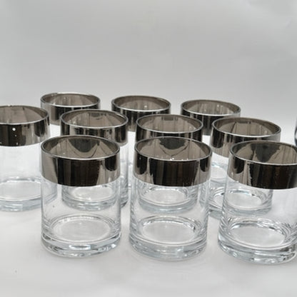MCM silver-rimmed rocks glasses clustered, showing the wide mirrored silver bands